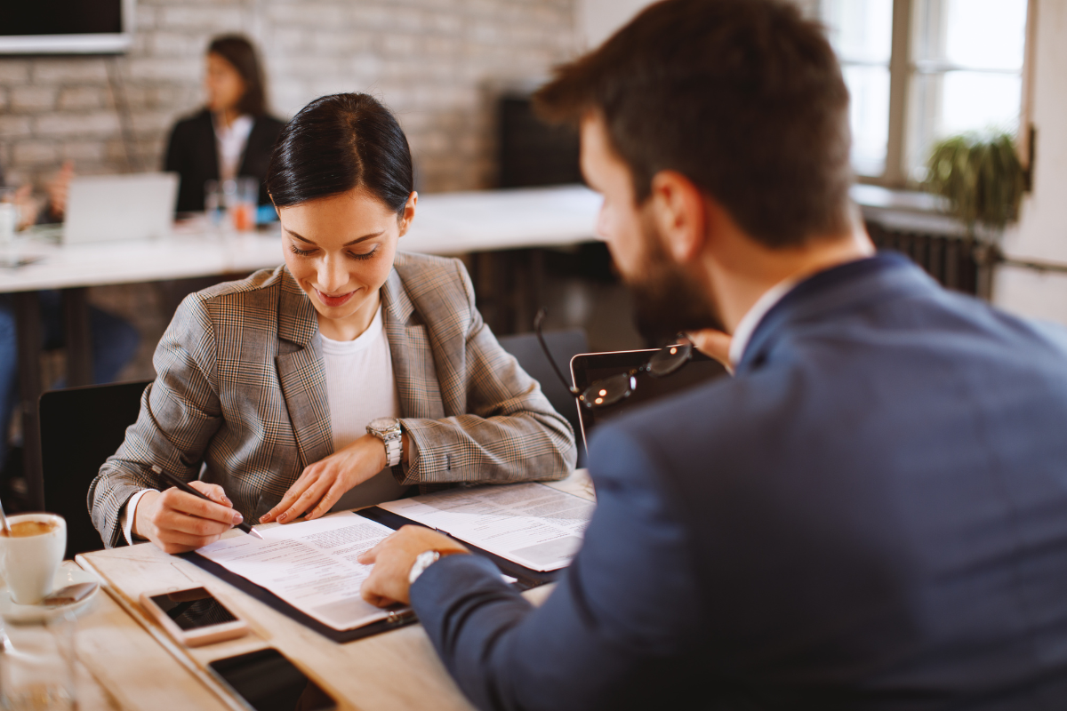 Lady signing contract in front of office worker