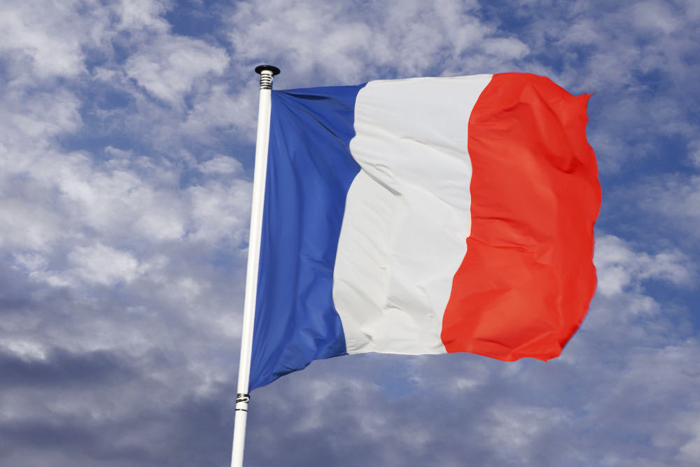 A French flag flying against a blue sky