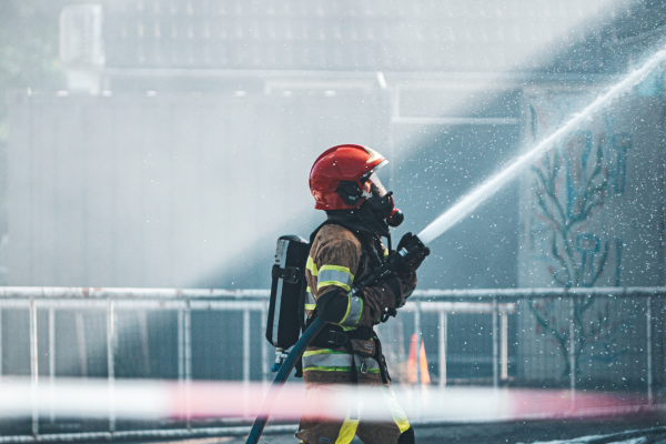 A firefighter in full gear aiming a water jet off screen
