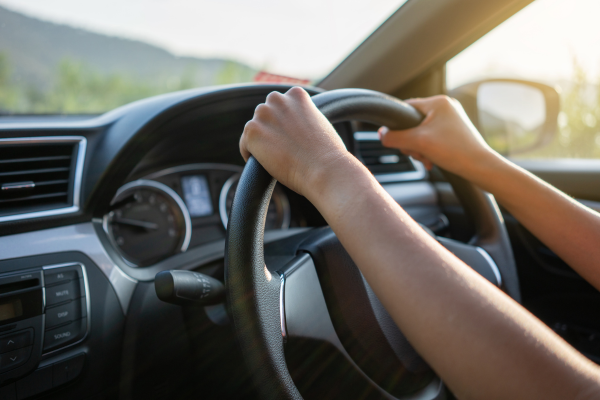 A person's hands on a steering wheel inside a car