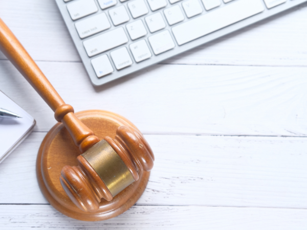 A photo looking down on a white wooden desk with a laptop keyboard and wooden gavel
