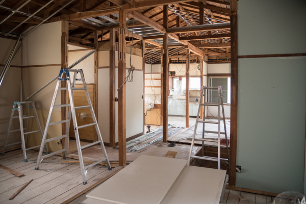 The inside of a house under construction, with tools like ladders, new panels and wiring strewn around