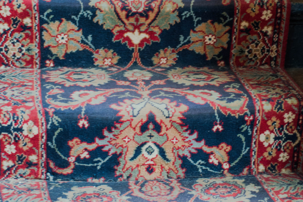 A close up of stairs carpeted with an intricate and traditional pattern, often seen in pubs