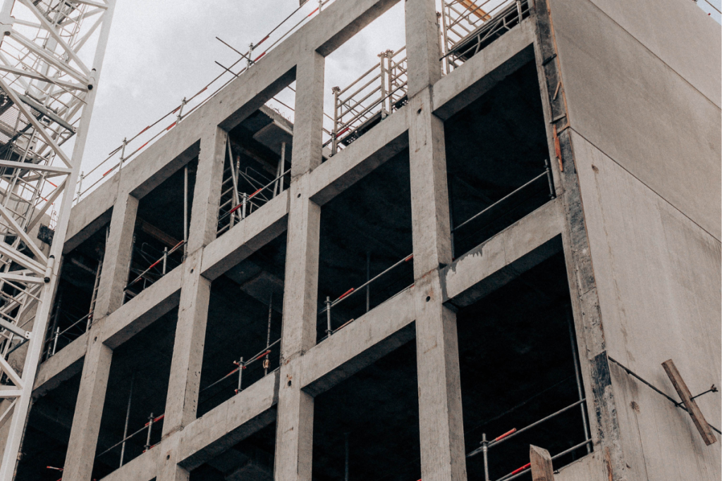 A concrete shell of a building being built with scaffolding, ladders and work equipment around it