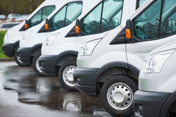 A fleet of white work vans all parked and lined up in a row