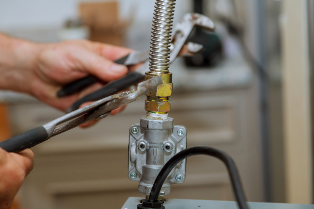 A close up of a gas valve being adjusted with a wrench by a gas fitter
