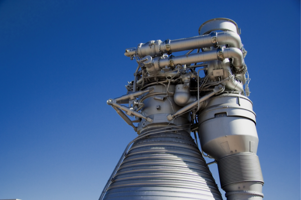 A large, metal rocket booster against a bright blue sky