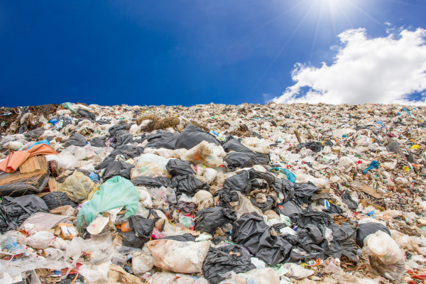 A photo of a full landfill containing all kinds of rubbish, and a beautiful blue sky