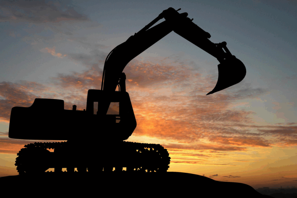 Dark sunset with an excavator on a hill