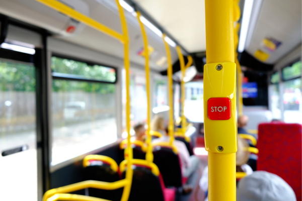 A photo from inside a London bus, with a yellow pole with a red "Stop" button in focus