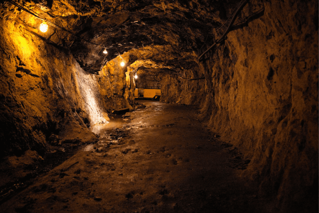 A dark underground gold mine tunnel with a bench in the middle of it