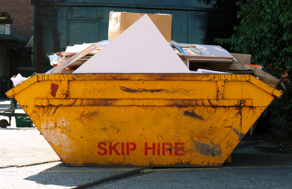 Skip with text 'skip hire' on, filled with waste
