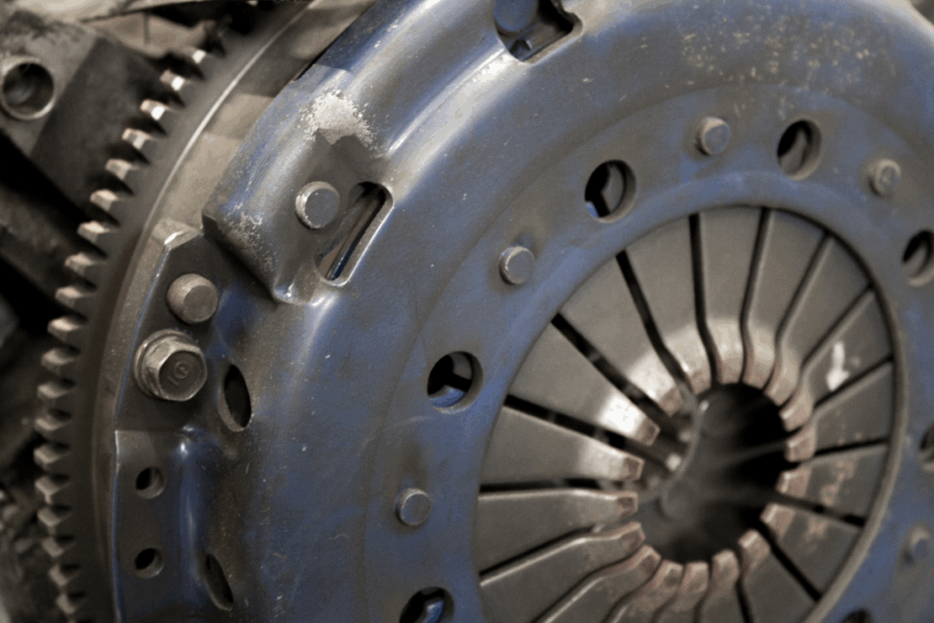 A close-up of a metal flywheel on a car which is located at the back of the engine.