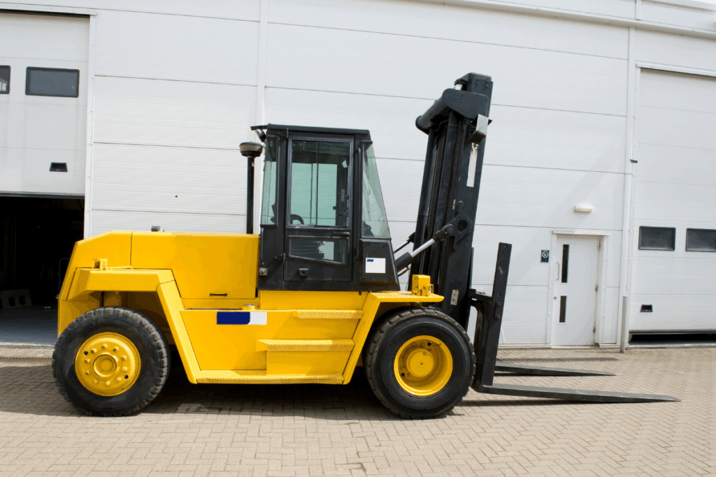 Yellow and black fork lift vehicle parked outside a white warehouse