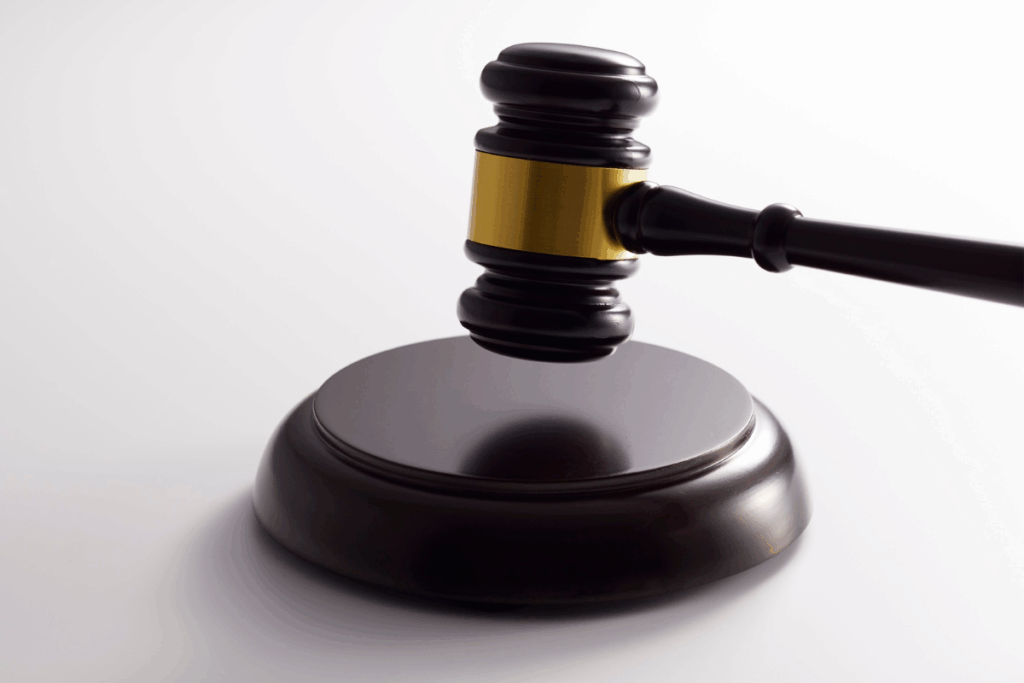 Brown wooden judge's gavel with gold detailing and white background