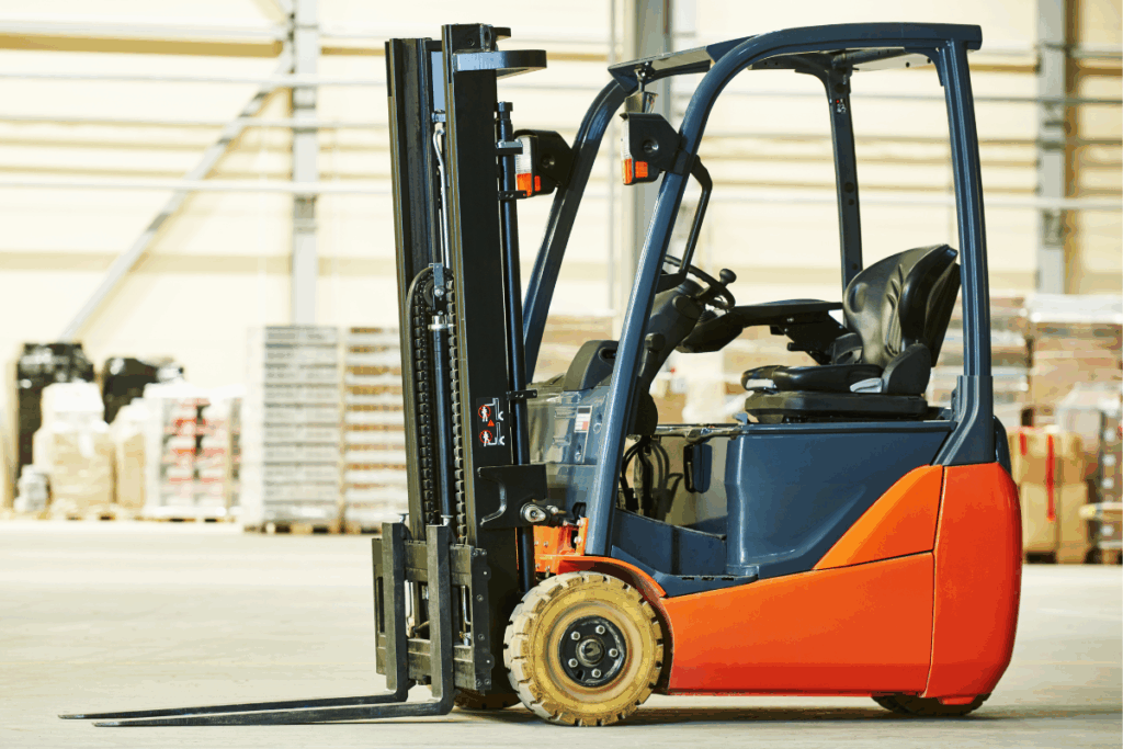 Orange and black forklift truck in a warehouse with concrete flooring