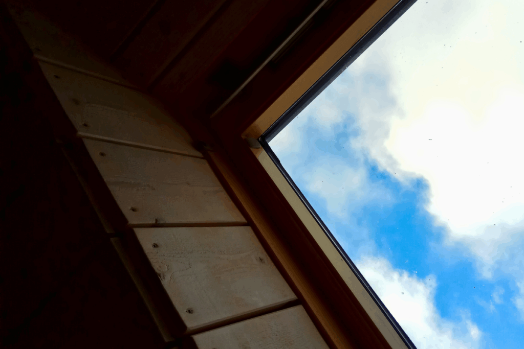 A skylight opening at a domestic property with blue sky and clouds showing through the glass