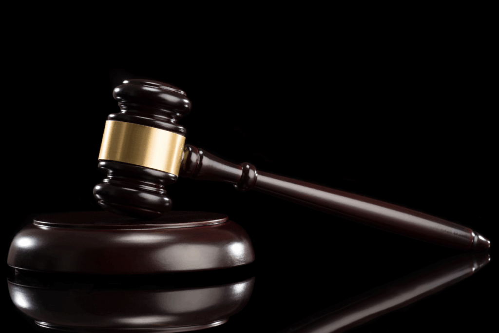 A judge's gavel with dark wood and gold metal on a black background with a shadow of the gavel