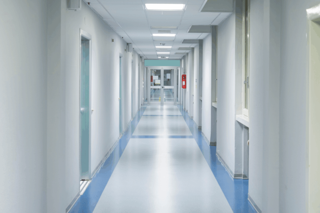 Hospital hallway with bright white walls and lighting and blue tiles on the floor edges