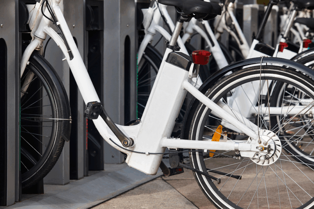 White electric bikes are parked at charging stations outside