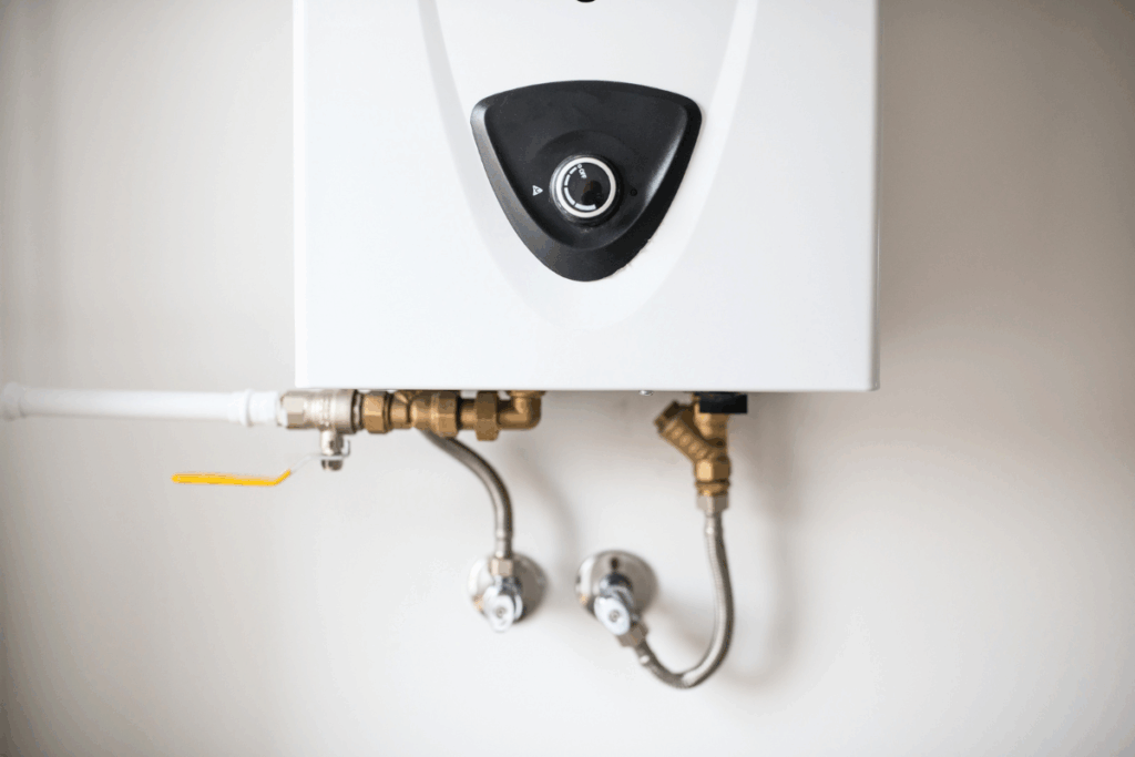A white gas boiler mounted to a wall in a residential building with brass pipes