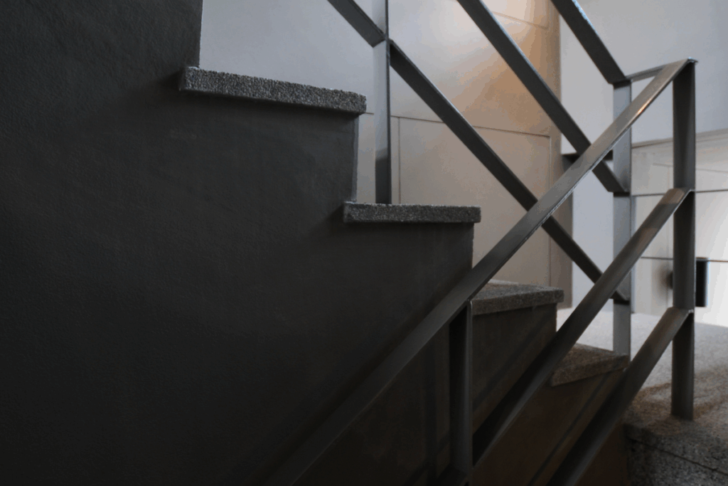 An open stairwell with a concrete floor and dark lighting shadowing the stairs