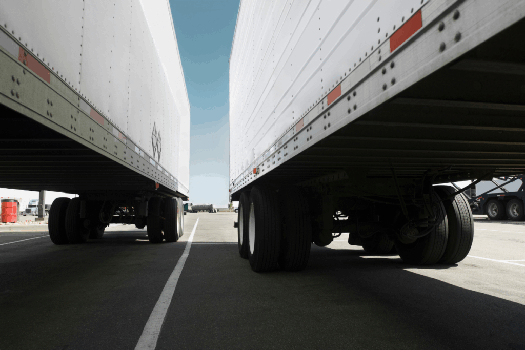 Two white trucks parked stationary in a car park with blue sky behind them