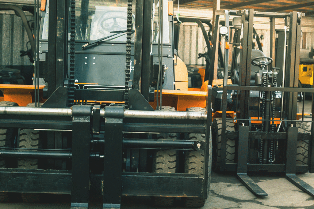 Orange and black Forklifts photographed from behind, parked stationary in a warehouse