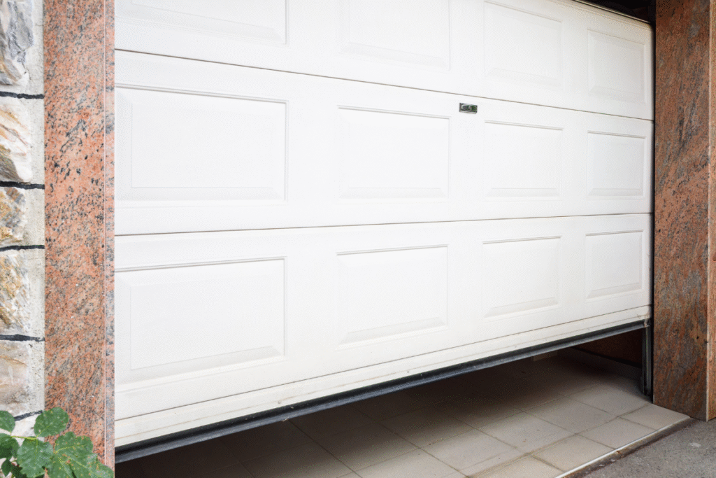 A white garage door at a domestic property with stone like design on the building