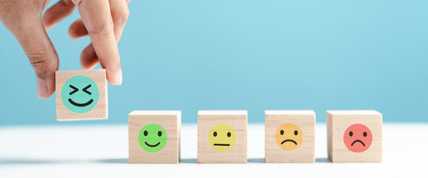 A series of wooden blocks in a row with a range of expressions from excited to depressed