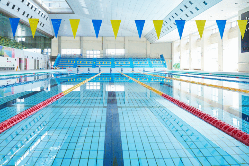 Empty swimming pool with blue tiles and bunting flags in yellow and blue hanging above the pool water