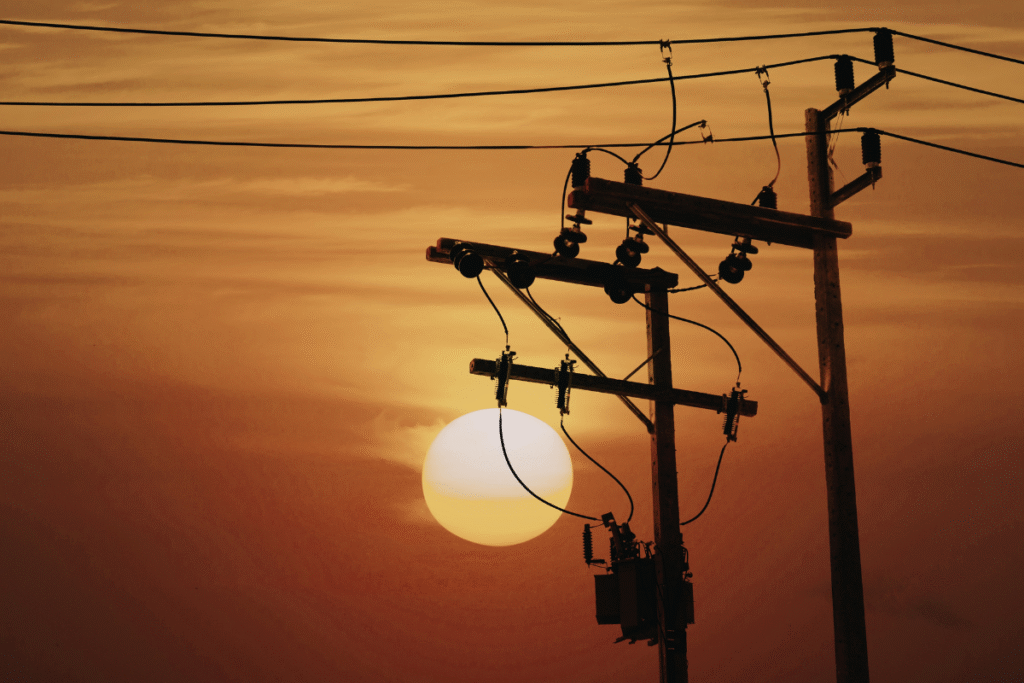 Overhead powerlines with orange sky and the sun in the background