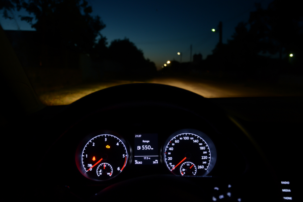 Car dashboard at night with headlights on