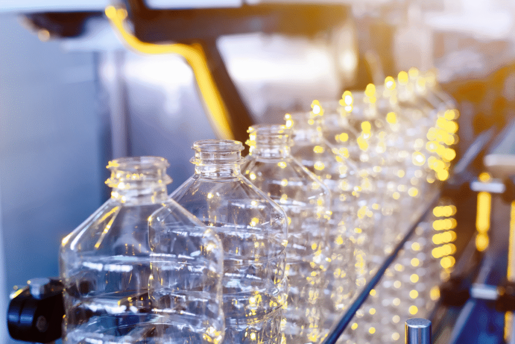 Plastic bottles lined up on a conveyor belt in a manufacturing warehouse