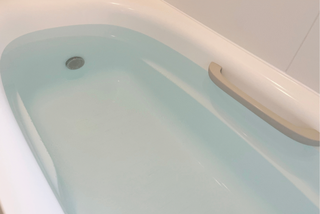 bath water filled in a white bathtub with a silver hand rail on the side