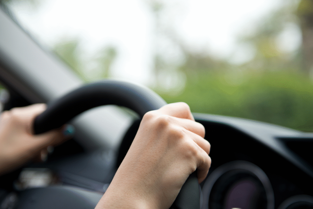 Hands on the top of a car steering wheel