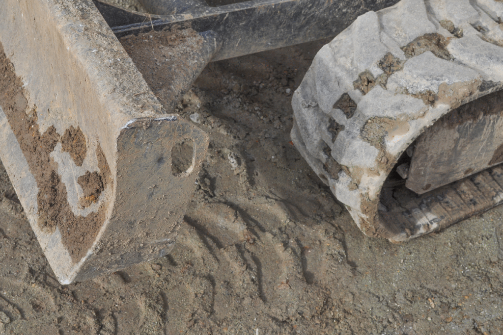 An excavator bucket and wheel digging a hole on site