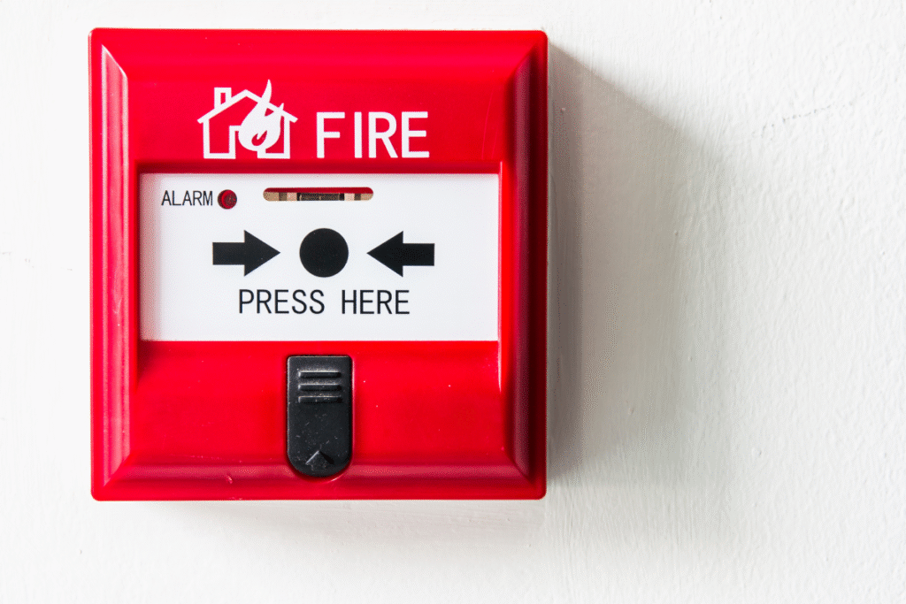 Red and white fire alarm attached to a white wall