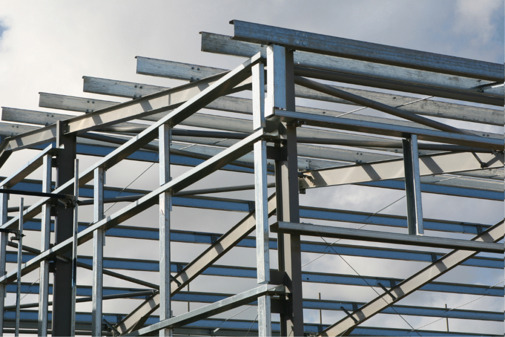 structural steel columns standing together with sky and clouds appearing through the back