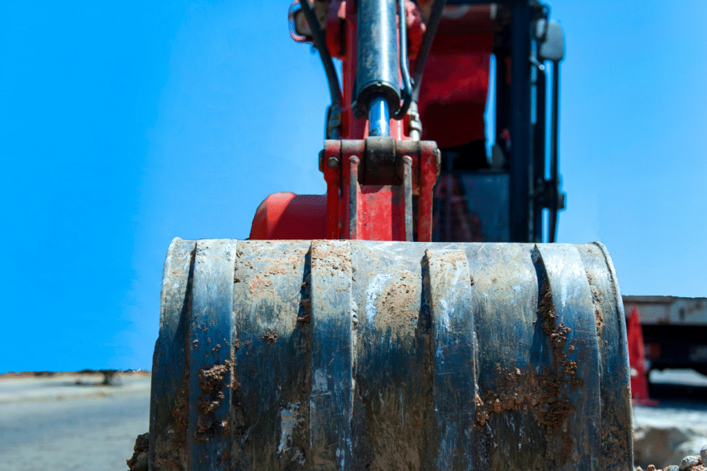 A red mini-excavator on site with blue sky behind it