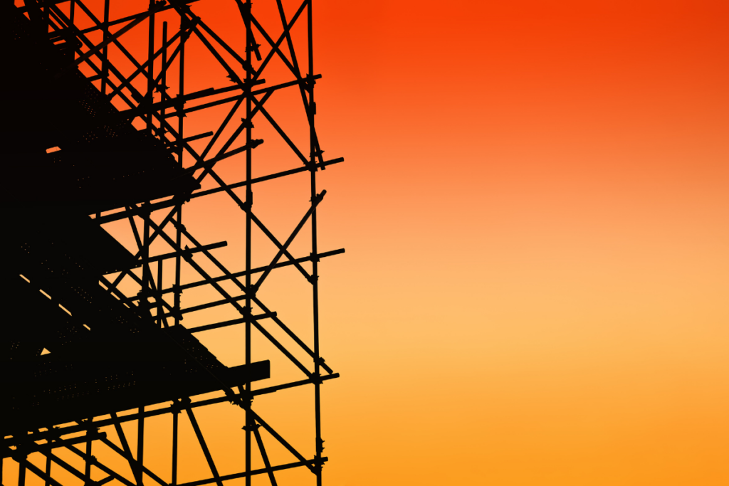 Scaffolding with an orange and red sunrise sky behind it