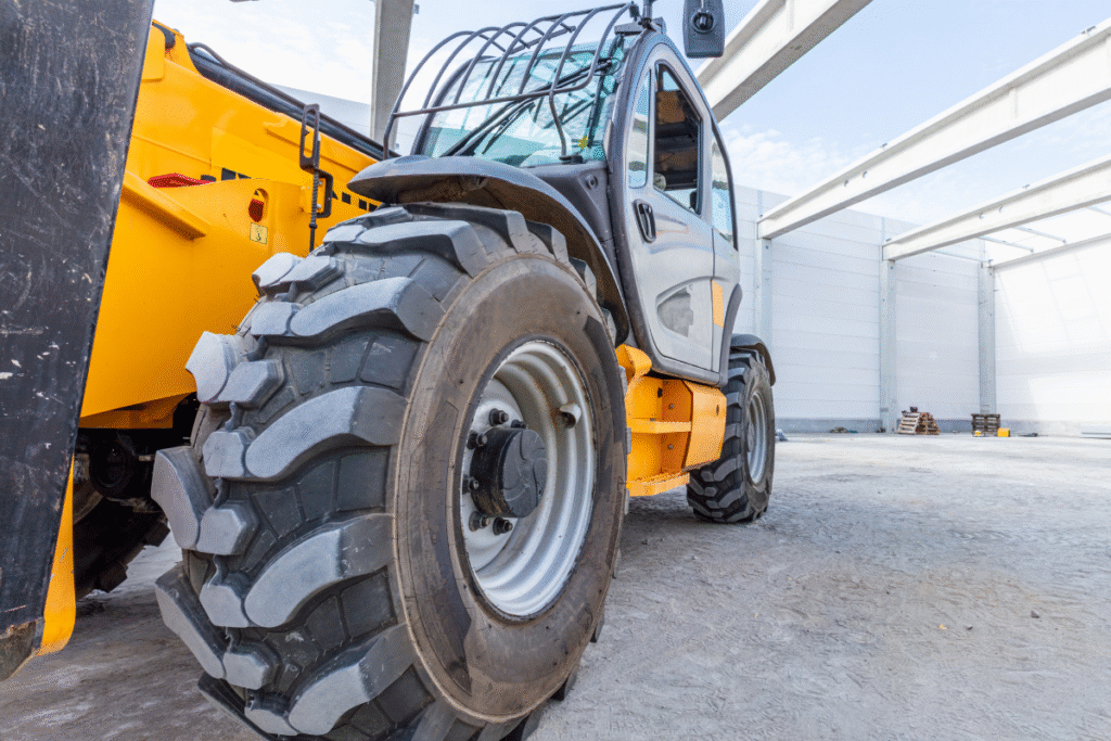 A yellow telehandler parked stationary on a concrete floor