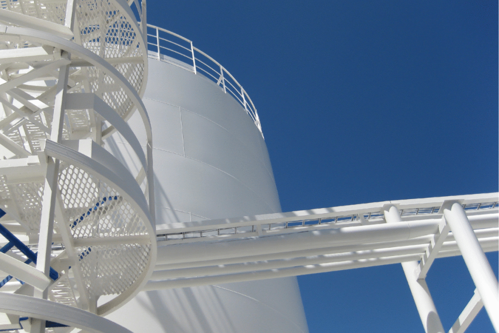 A large industrial white water tank with blue clear sky behind it