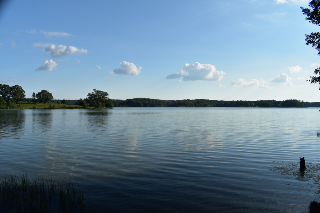 reservoir with blue sky and clouds and greenery surrounding it