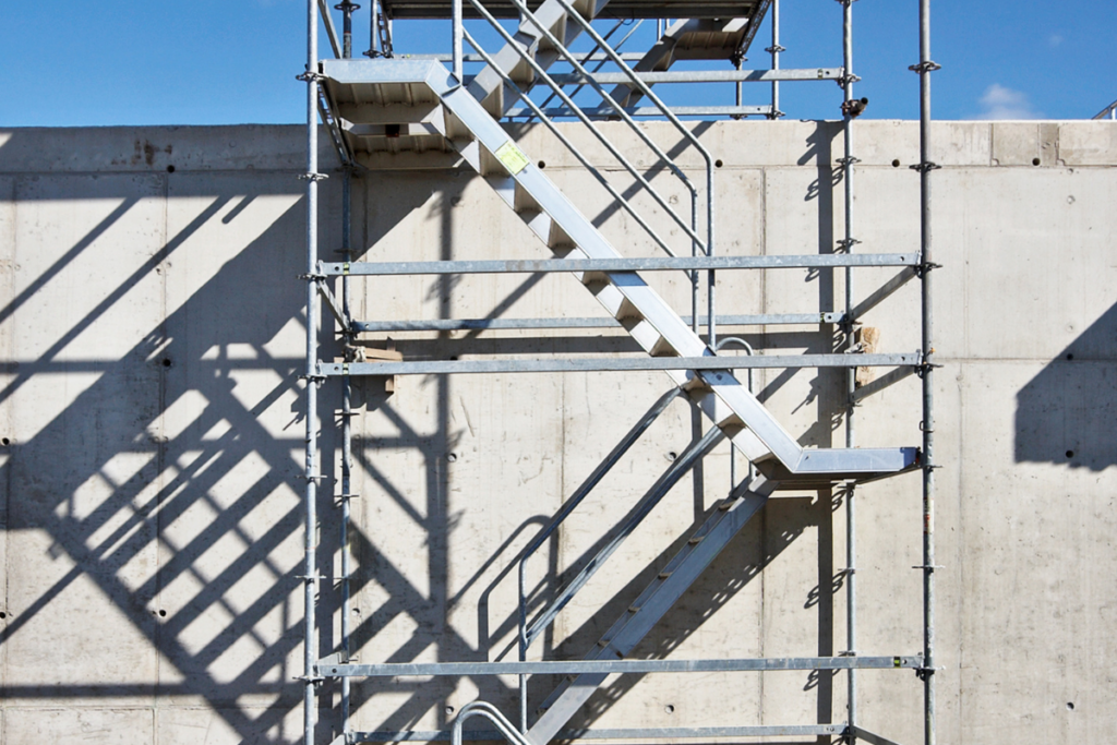 mobile scaffold on the side of a concrete wall with blue sky